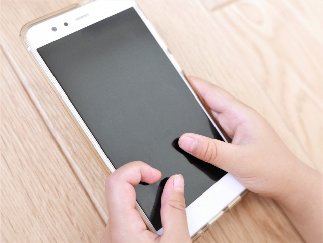 スマホを手でいじっている様